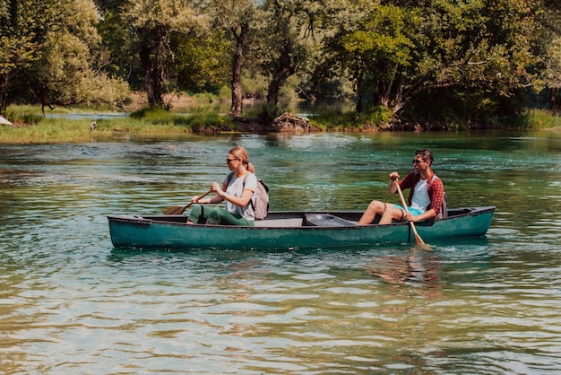 Un couple d'amis explorateurs aventureux fait du canoë dans une rivière sauvage entourée par la belle nature.