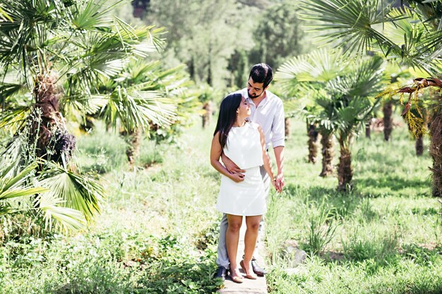 Photo un couple en amour alors qu'ils se tiennent sur le trottoir au milieu des arbres et des plantes dans le parc