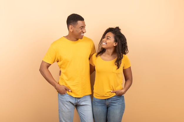 Couple amoureux afro-américain aimant embrassant regardant et souriant les uns aux autres posant sur fond de pêche