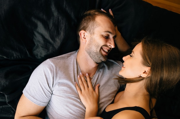 Un couple amoureux allongé sur un lit en train de câliner