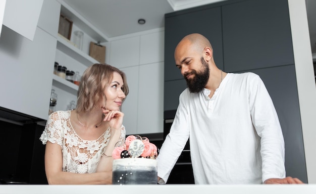 Couple d'amoureux amoureux dans la cuisine avec un anniversaire de gâteau ou un anniversaire