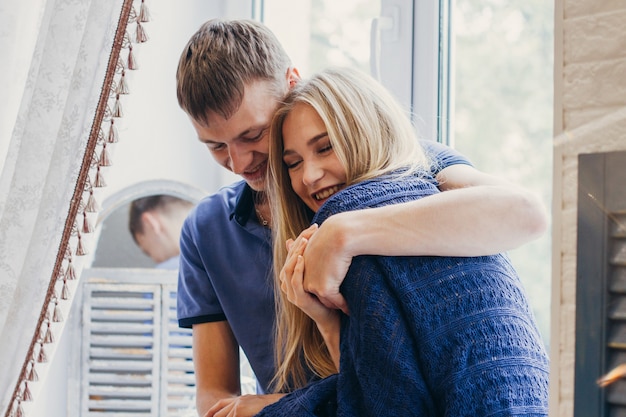 Couple d'amoureux assis sur la fenêtre, regard affectueux et doux. Émotion positive, visages souriants. Couple s'embrassant et se regardant. Un homme et une femme s'aiment