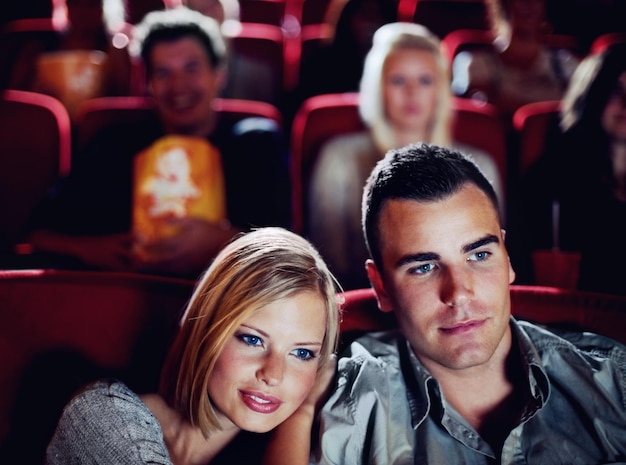 Couple d'amoureux au cinéma ou au cinéma pour regarder un film de divertissement ensemble au cinéma lors d'un rendez-vous romantique Les jeunes gens heureux sourient la romance et les relations au cinéma