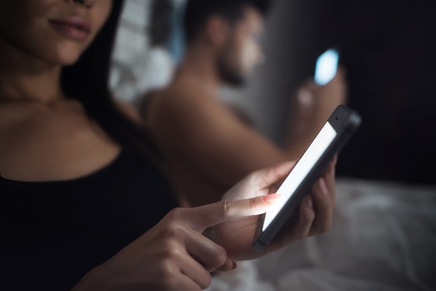 Couple amoureux au lit avec téléphone portable la nuit