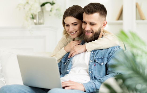 Couple d'amoureux ayant un appel vidéo sur un ordinateur portable se détendre à la maison