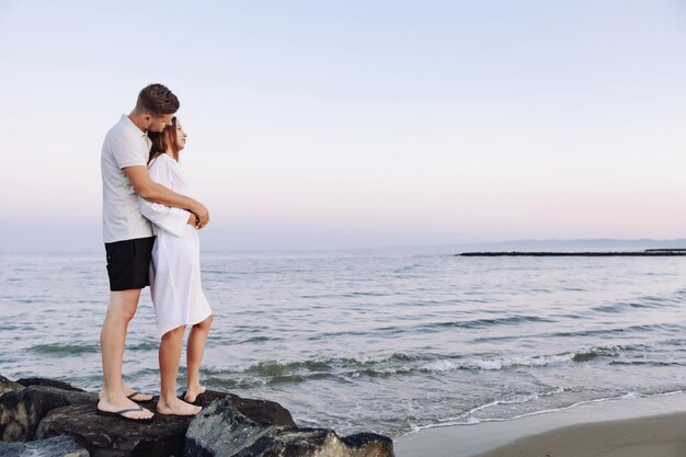 Couple amoureux ayant des moments tendres romantiques au coucher du soleil sur la plage