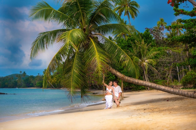 Couple amoureux sur une balançoire sous un palmier sur la plage