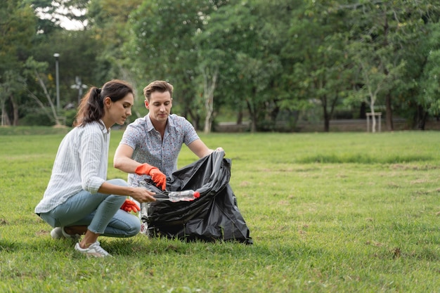 Couple d'amoureux bénévoles portant des gants marchant pour ramasser les ordures dans le parc Pour garder l'environnement propre