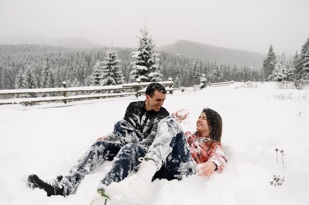 Couple d'amoureux en chemise lors d'une promenade hivernale. Homme et femme s'amusant dans la forêt givrée. Rendez-vous romantique en hiver. Ambiance de Noël d'une jeune famille. Histoire d'amour d'hiver