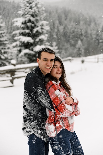 Couple d'amoureux en chemise lors d'une promenade hivernale. Homme et femme s'amusant dans la forêt givrée. Rendez-vous romantique en hiver. Ambiance de Noël d'une jeune famille. Histoire d'amour d'hiver