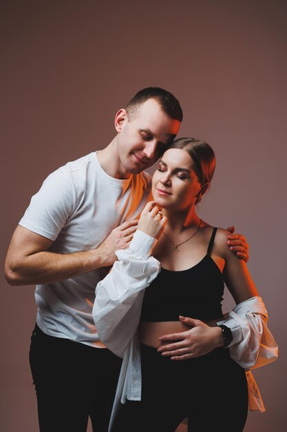 Un couple amoureux en chemises blanches s'embrassent et s'amusent Un couple élégant s'embrasse sur fond blanc Concept de famille heureuse