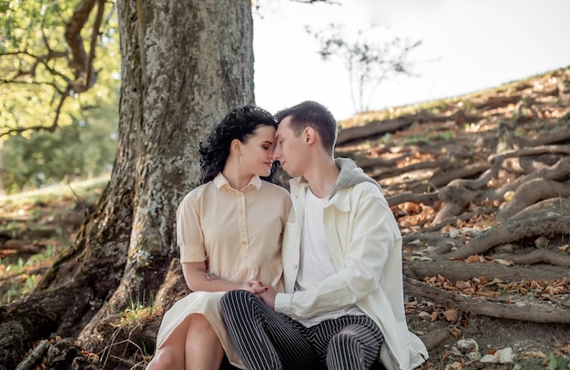 Un couple amoureux, un couple et une fille s'assoient sous un bel arbre et se caressent, s'embrassent