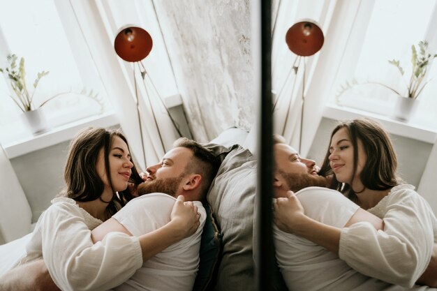 Couple amoureux dans la chambre. Brune mince. Intérieur élégant.