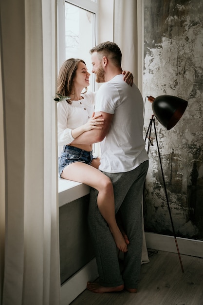 Couple amoureux dans la chambre. Brune mince. Intérieur élégant.