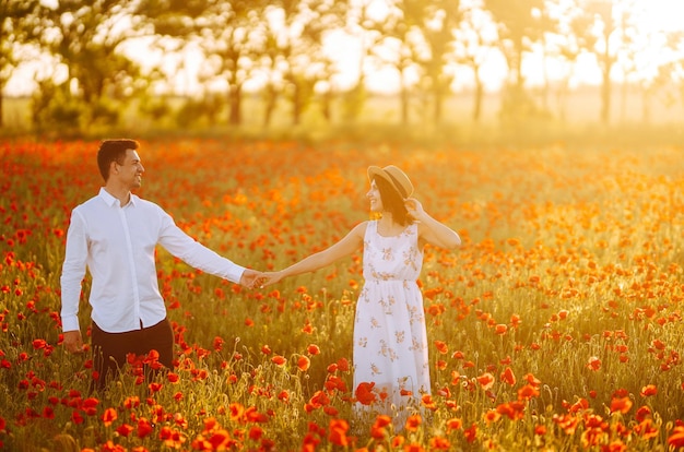 Couple d'amoureux dans le champ de coquelicots au coucher du soleil Profiter du temps ensemble amour et style de vie