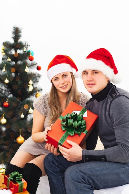 Un couple d'amoureux dans des chapeaux de Noël avec des cadeaux de Noël