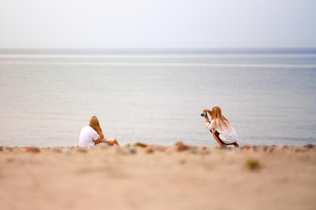 Couple amoureux dans les coulisses de la séance photo en plein air photographe professionnelle prise de vue d'un couple d'amoureux sur fond de mer de plage Mariage histoire d'amour séance photo bel horizon de paysage marin