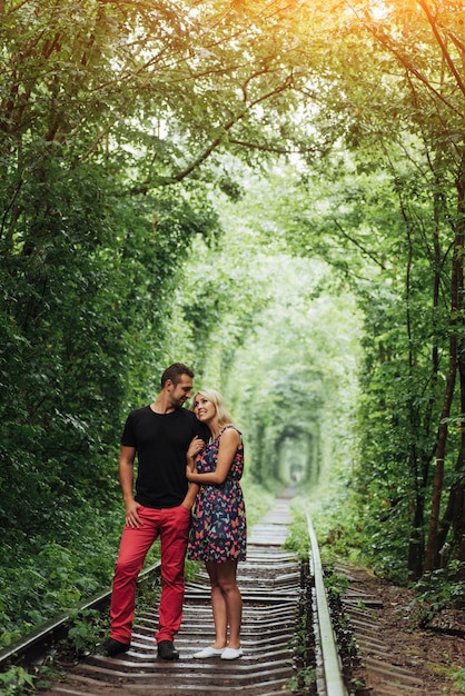 Couple d'amoureux dans un tunnel d'arbres verts sur chemin de fer