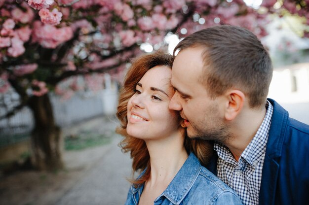 Couple amoureux dans un verger de pommiers en fleurs allongé sur la couverture