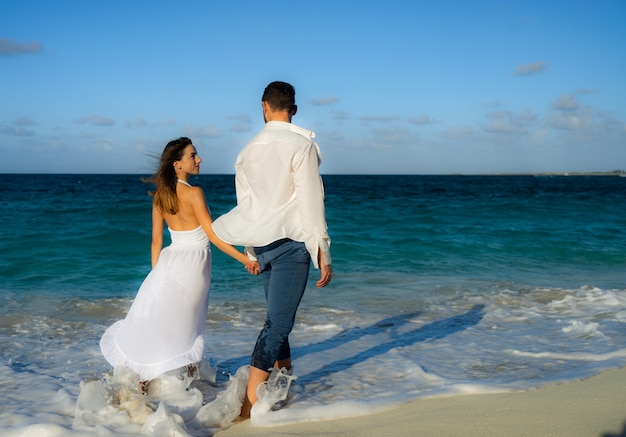 Couple d'amoureux dansant sur le sable sur la plage de la mer en été contre l'eau cristalline