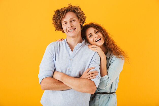 Couple d'amoureux debout isolé sur fond jaune à la caméra.