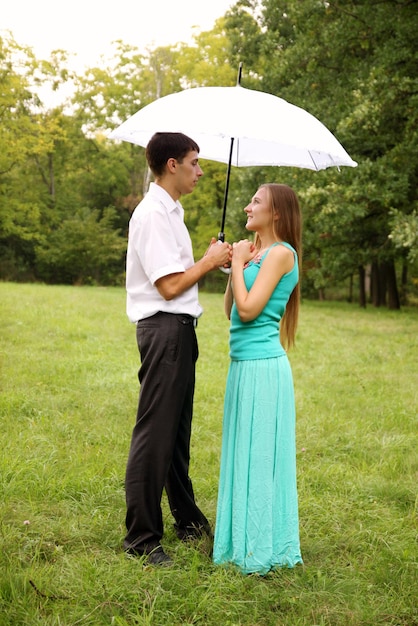 Couple d'amoureux debout sous un parapluie blanc