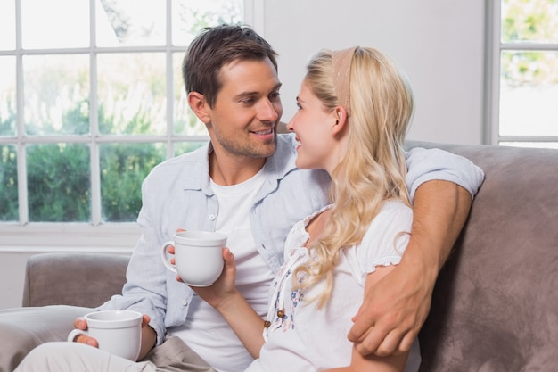 Couple d&#39;amoureux détendu avec des tasses de café assis sur un canapé