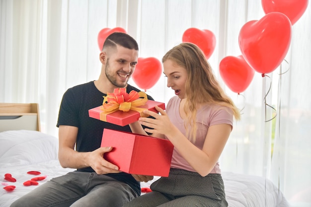 Couple amoureux donnant coffret cadeau dans le bonheur de la chambre dans le concept de la Saint-Valentin amour