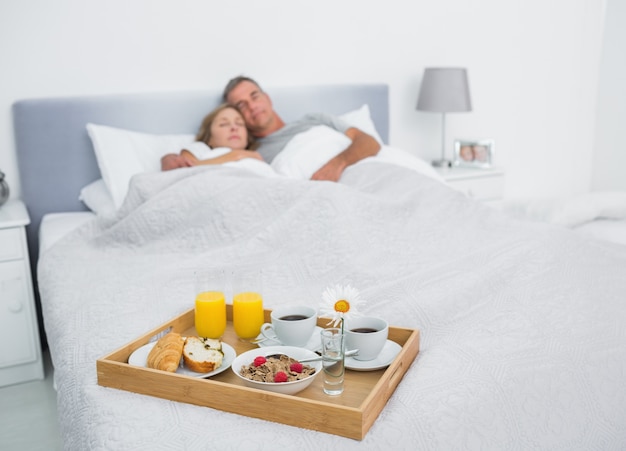 Couple d&#39;amoureux dormir avec plateau de petit déjeuner sur le lit