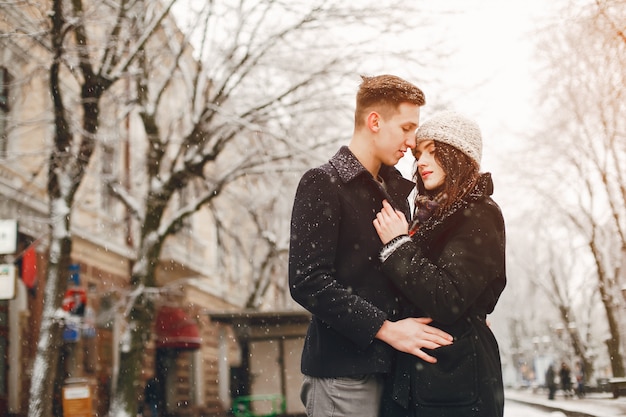 couple d&#39;amoureux élégant en manteaux noirs marchant dans la ville de neige d&#39;hiver