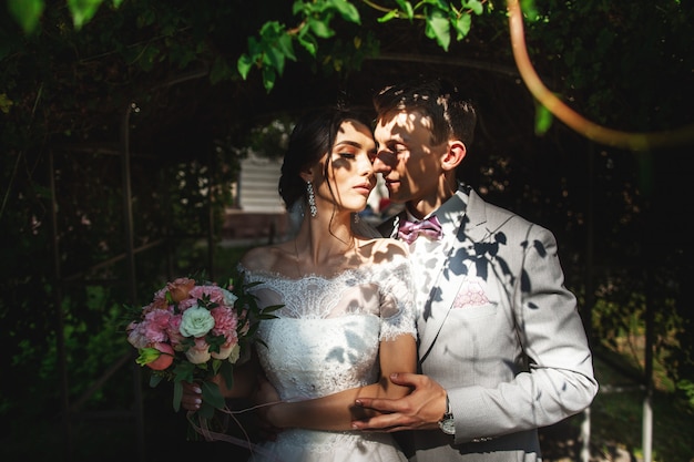 Un couple d'amoureux embrasse doucement les jeunes mariés à l'ombre des arbres