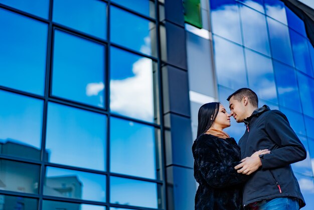 Couple amoureux enlacés par un gratte-ciel aux vitres en miroir