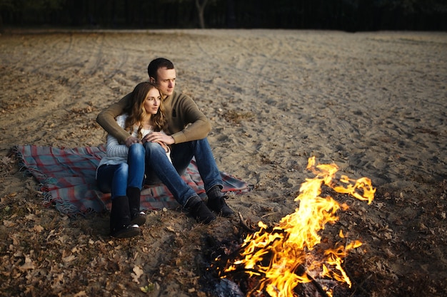 Couple amoureux est assis près du feu à proximité et se réchauffe