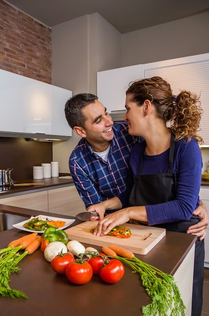 Couple amoureux étreignant et préparant des légumes sains dans la cuisine. Concept de mode de vie familial moderne.