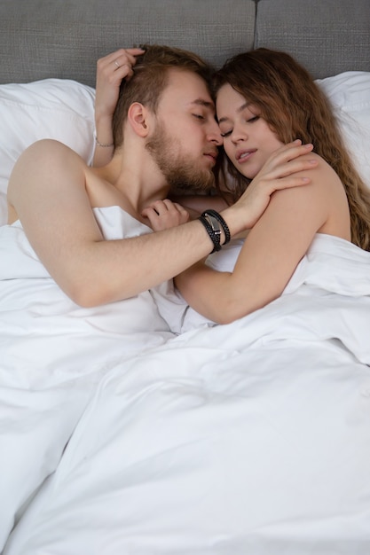 couple amoureux étreindre en position couchée dans son lit