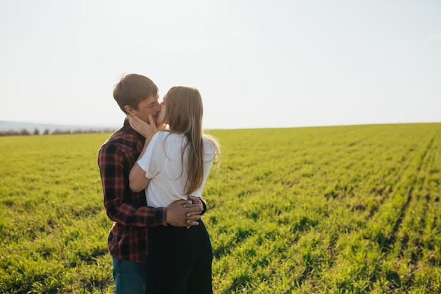 Couple d'amoureux étreint et s'embrasse sur la verte prairie au printemps ensoleillé. Amour, jeunesse, concept de bonheur.