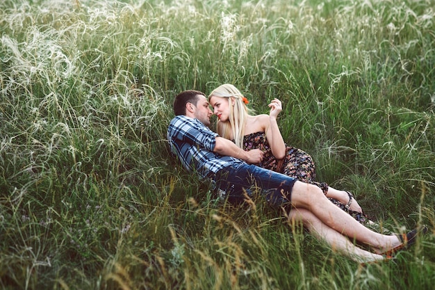 Couple amoureux fille blonde et mec dans l'herbe