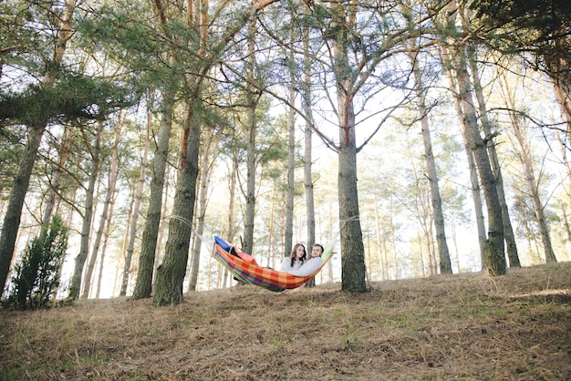 Couple amoureux, fille et gars dans un hamac jouit dans les bois, concept d'histoire d'amour de voyage