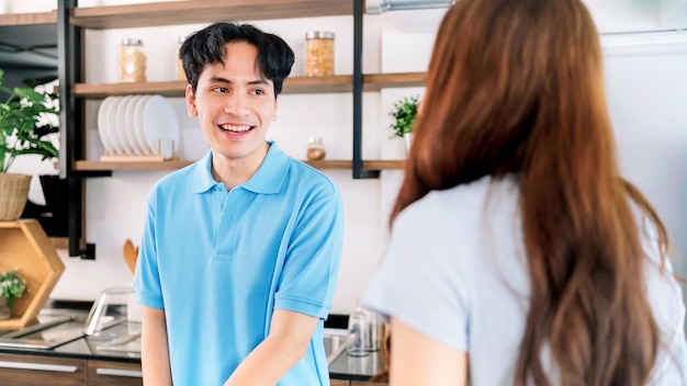 Couple d'amoureux gai asiatique gros plan sur un homme parlant de préparer et de cuisiner avec joie tout en se tenant sur un comptoir de cuisine à la maison Cuisiner ensemble dans leurs cuisines à domicile