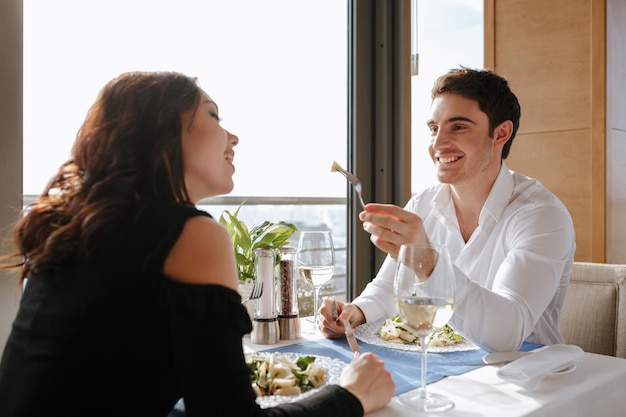 Couple d'amoureux gai assis au restaurant et manger.