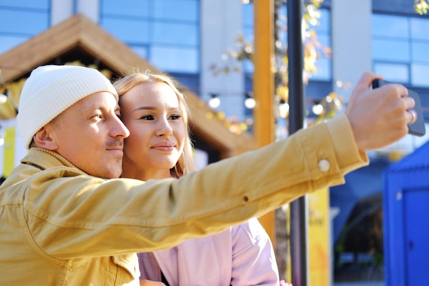 Un couple amoureux un gars et une fille prennent un selfie ensemble par temps ensoleillé couple regardant la caméra et souriant