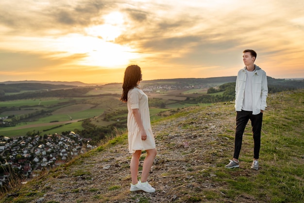 Un couple amoureux, un gars et une fille se tiennent sur une montagne au coucher du soleil, s'embrassent et s'embrassent