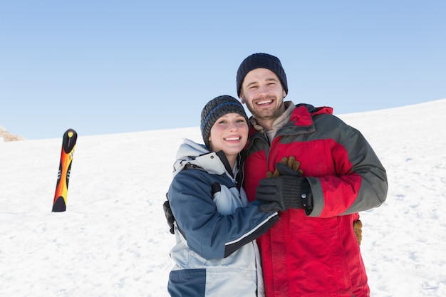 Couple d&#39;amoureux heureux avec planche de ski sur la neige en arrière-plan