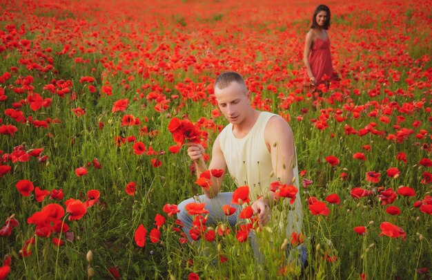 Couple amoureux insouciant amoureux sur le champ d'été de pavot. Bien être familial, campagne nature.