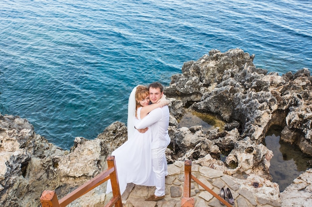 Couple, amoureux, jeune, mariée marié, habillé, dans, blanc, étreindre, sur, falaise