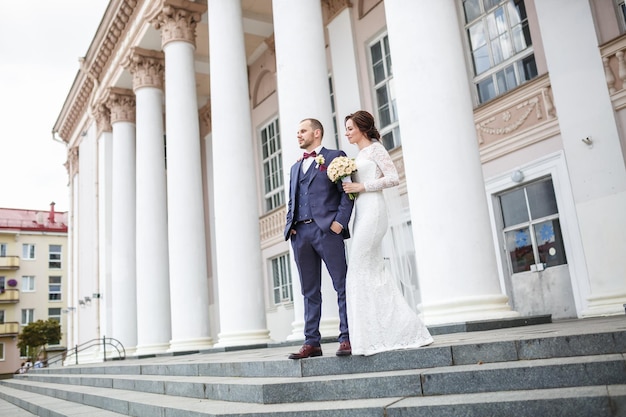 Un couple d'amoureux de jeunes mariés se promène dans la vieille ville près des colonnes le jour du mariage