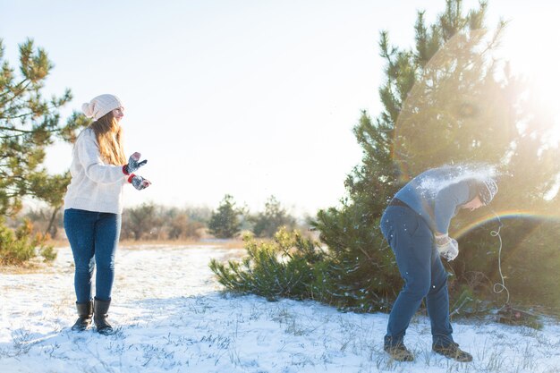 Couple d'amoureux joue aux boules de neige en hiver dans la forêt