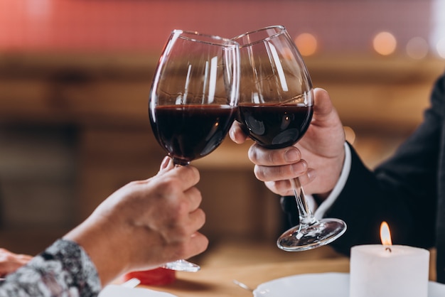 Couple amoureux lève des verres de vin rouge