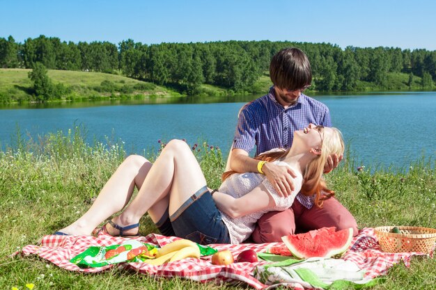 Couple amoureux lors d'un pique-nique au bord du lac