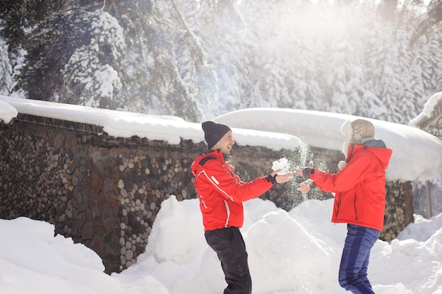 Couple amoureux main dans la main et jouant avec la neige en plein air en hiver.